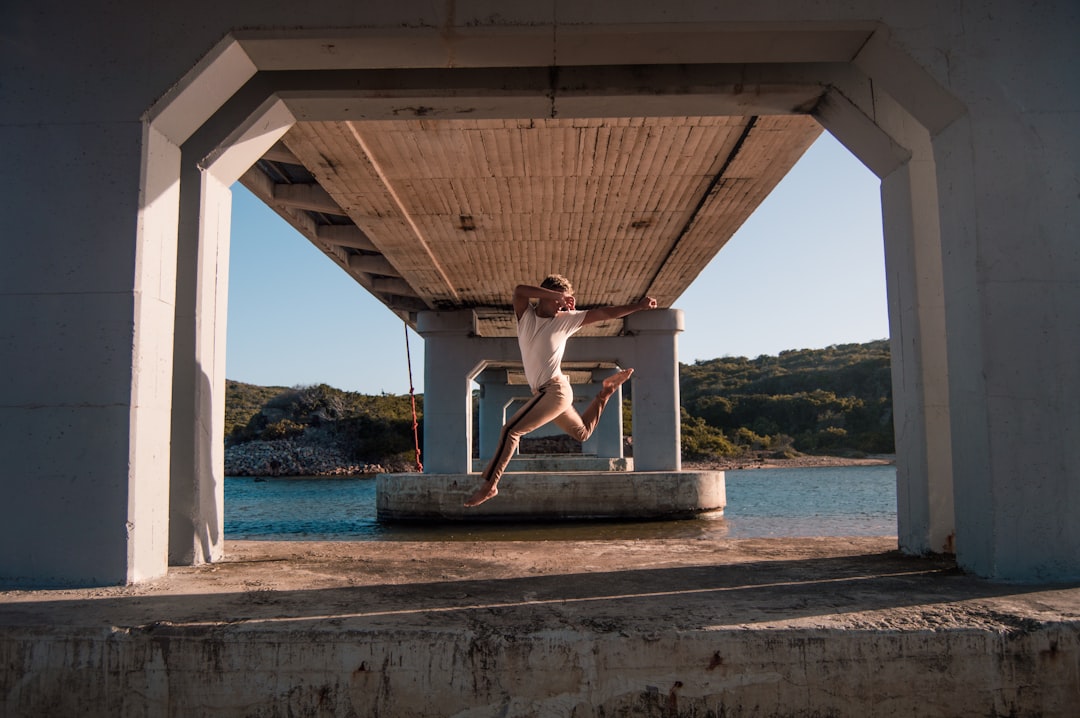 woman in white bikini jumping on brown wooden dock during daytime