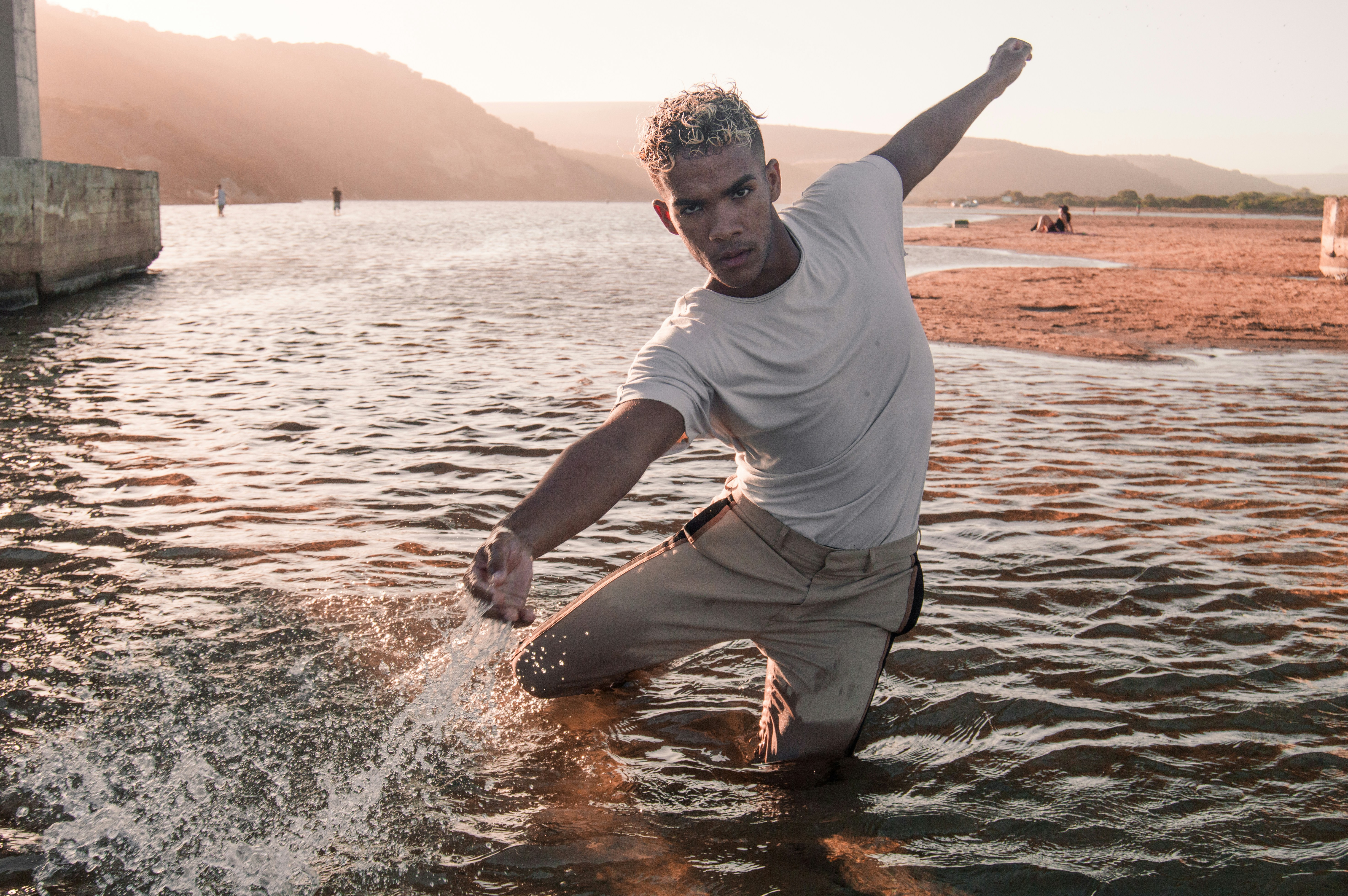 man in white crew neck t-shirt and brown shorts standing on water during daytime