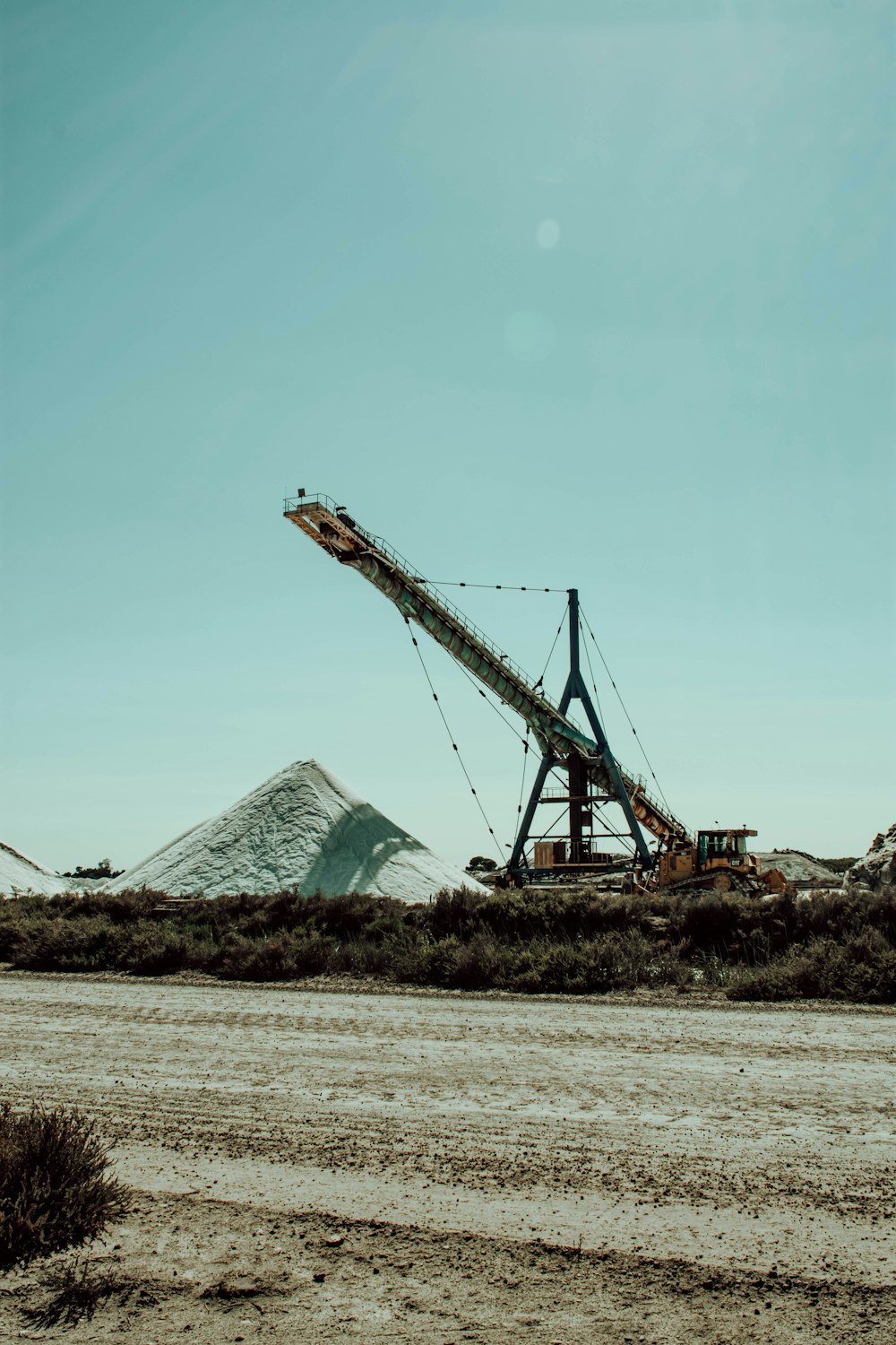 brown metal crane near white and gray house under blue sky during daytime