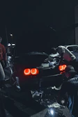man in red jacket standing beside black car