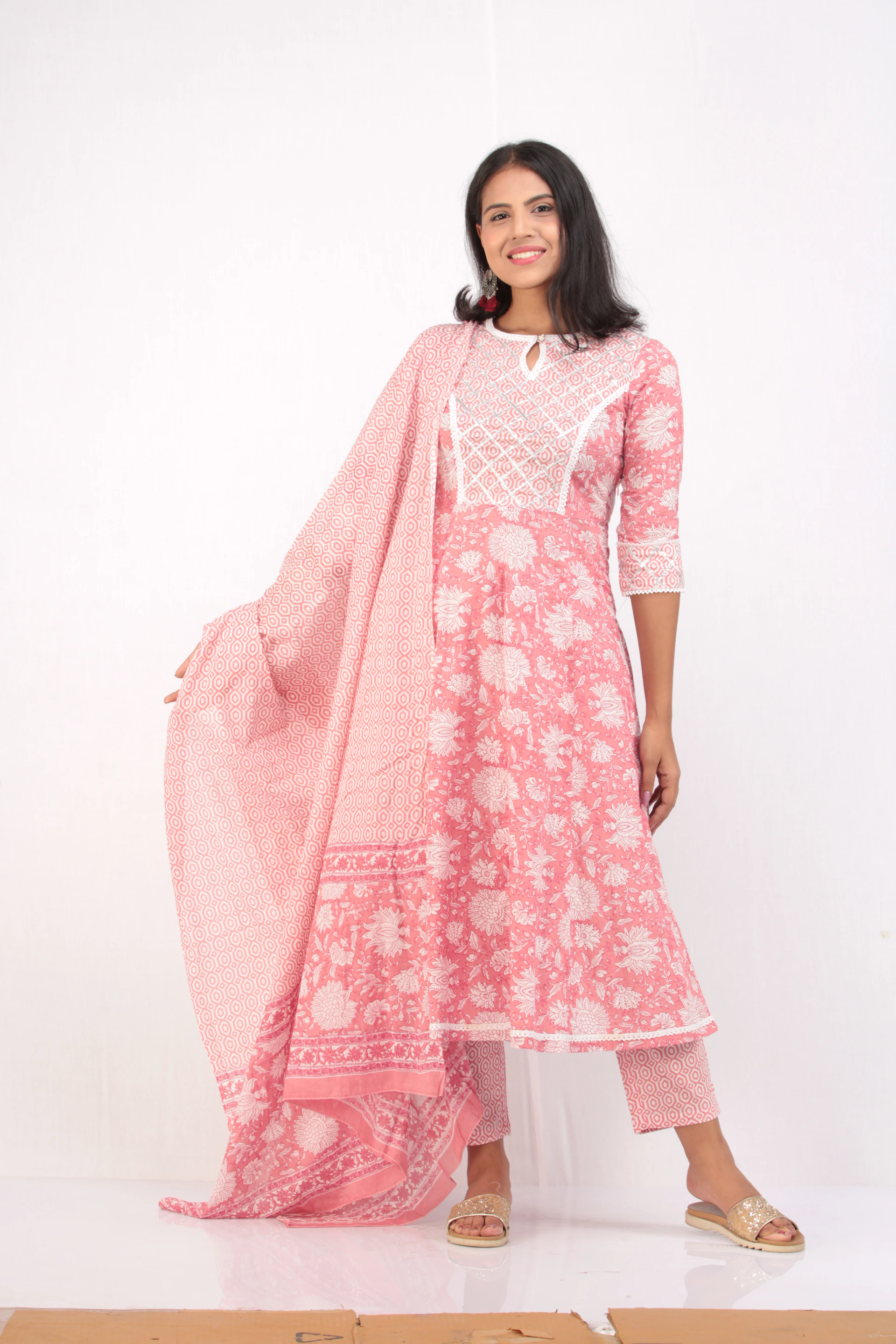 A cheerful model wearing a stylish kurti and churidar set, standing against a bright, minimalist background.