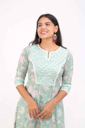 Model wearing a flowing dress paired with handcrafted earrings, smiling outdoors.