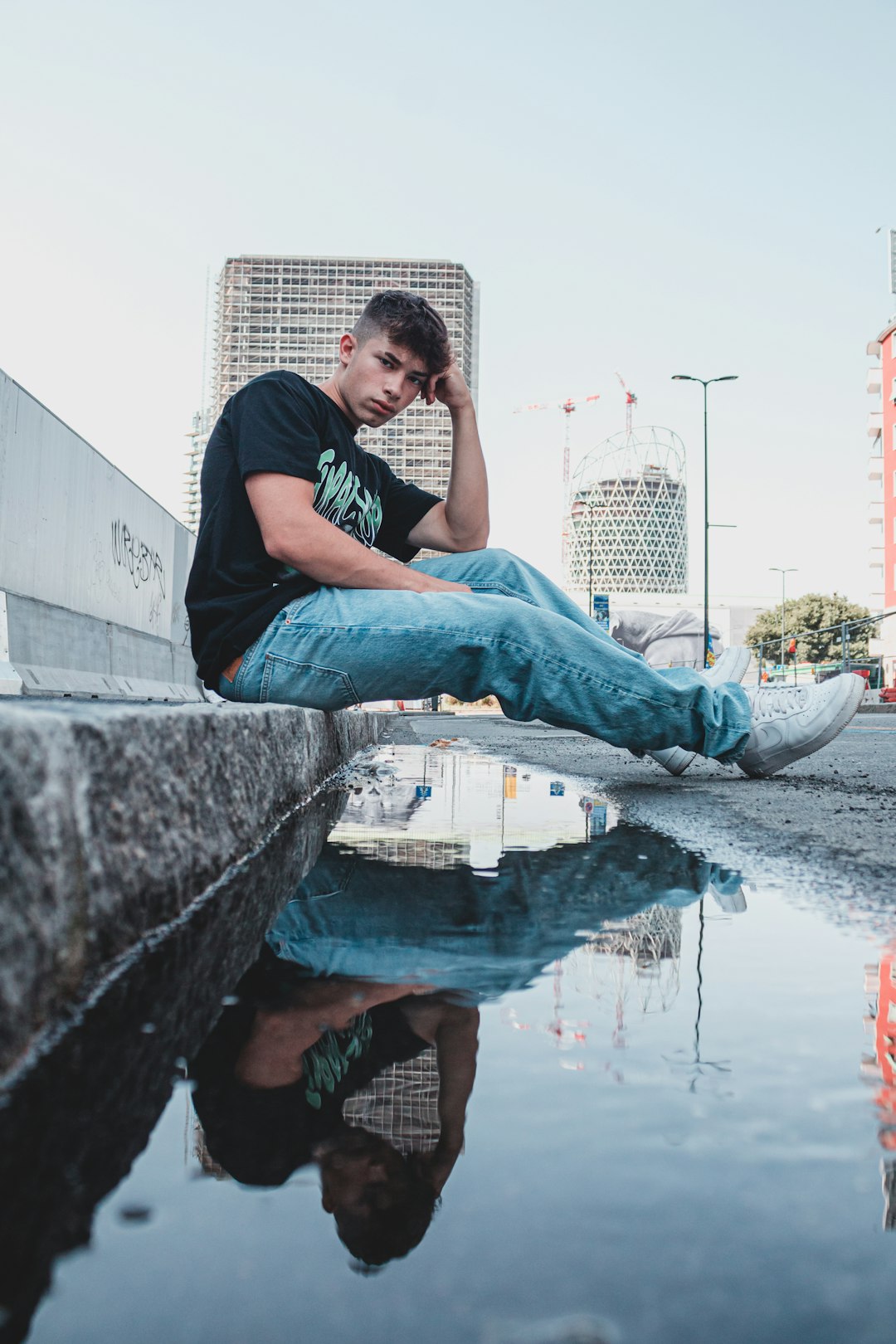 man in black t-shirt and blue denim jeans sitting on concrete bench during daytime