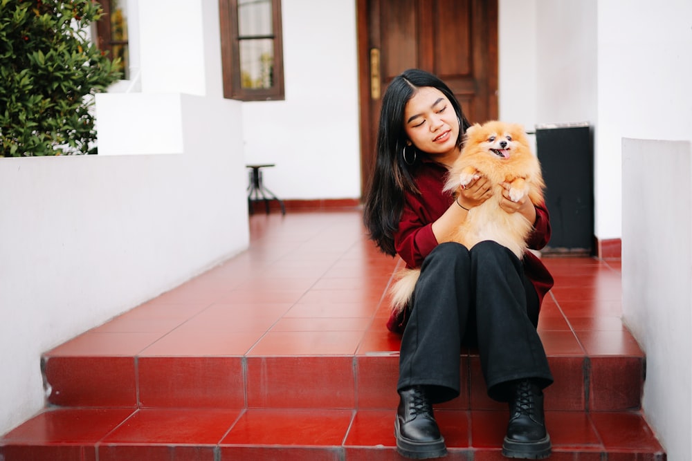 woman in black long sleeve dress holding brown long coated dog