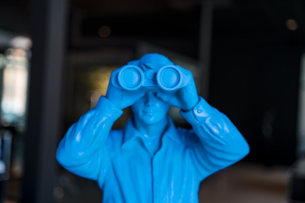 person in blue long sleeve shirt holding blue binoculars