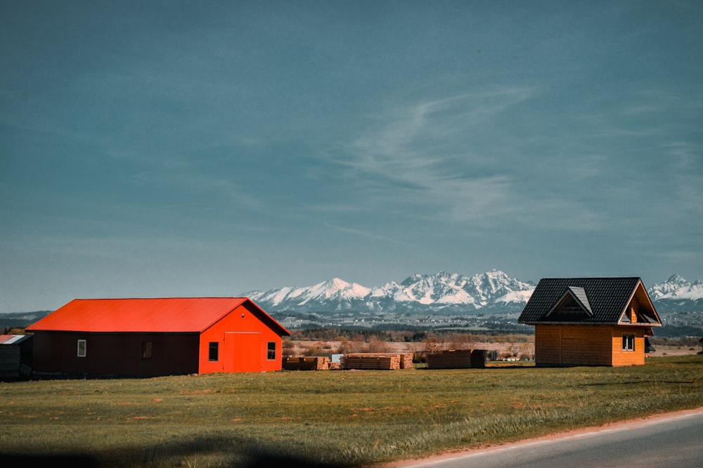 Granero rojo y negro cerca de un campo de hierba marrón y montañas cubiertas de nieve durante el día