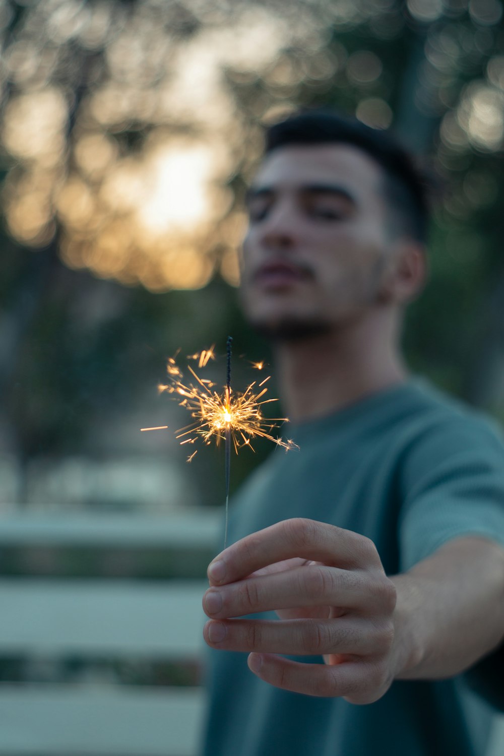 man in blue crew neck shirt holding sparkler