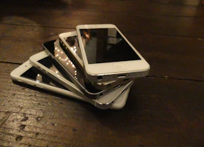 A variety of smartphones arranged neatly on a wooden table with price labels visible