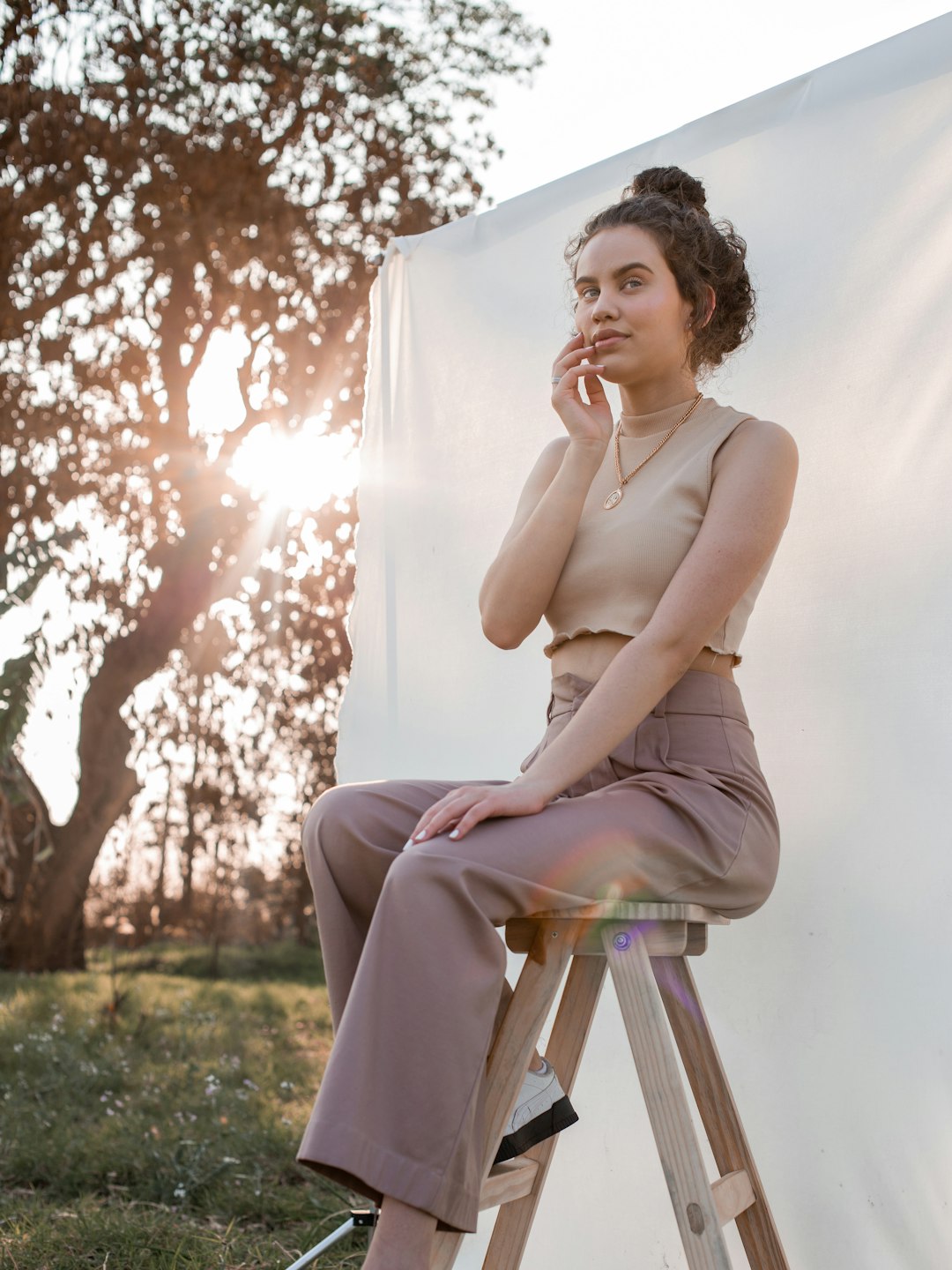 woman in white tank top sitting on brown wooden folding chair during daytime