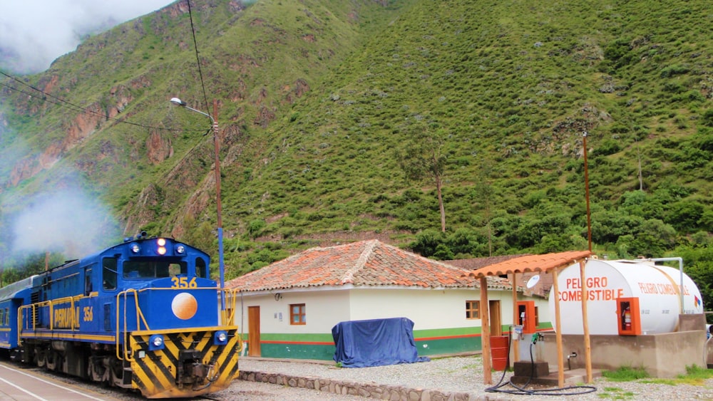 blue and yellow train near brown wooden house during daytime