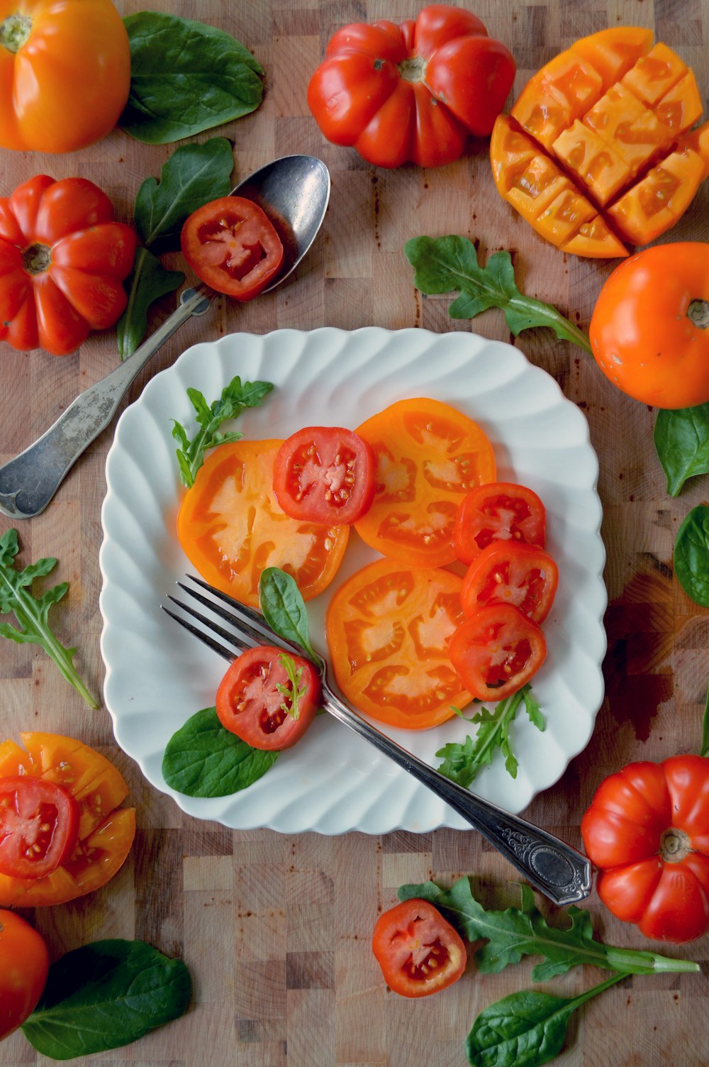 sliced tomato on white ceramic plate beside stainless steel fork and knife