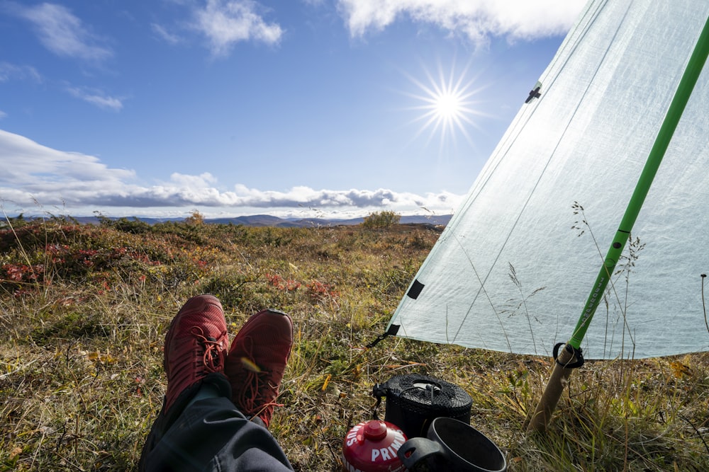 person in black pants and red shoes sitting near white tent during daytime