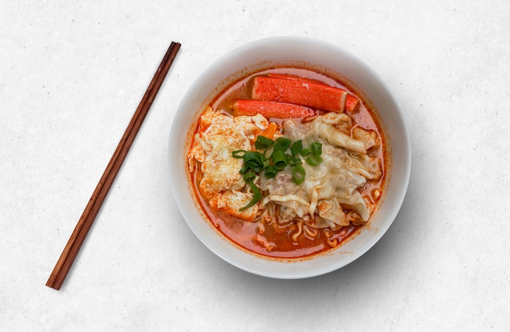 white ceramic bowl with soup and chopsticks