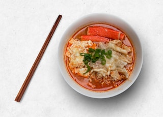 white ceramic bowl with soup and chopsticks