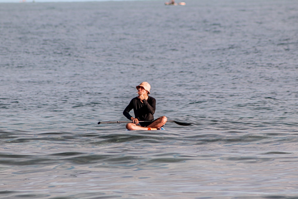 woman in black long sleeve shirt and black pants sitting on white surfboard on body of on on on on