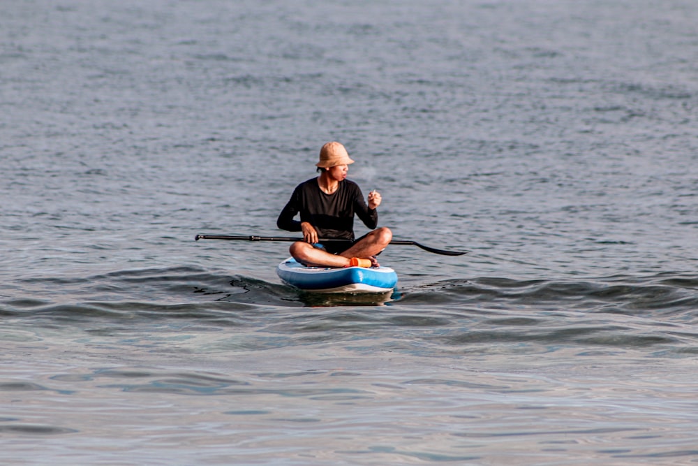 man in black shirt and blue shorts riding blue kayak on body of water during daytime