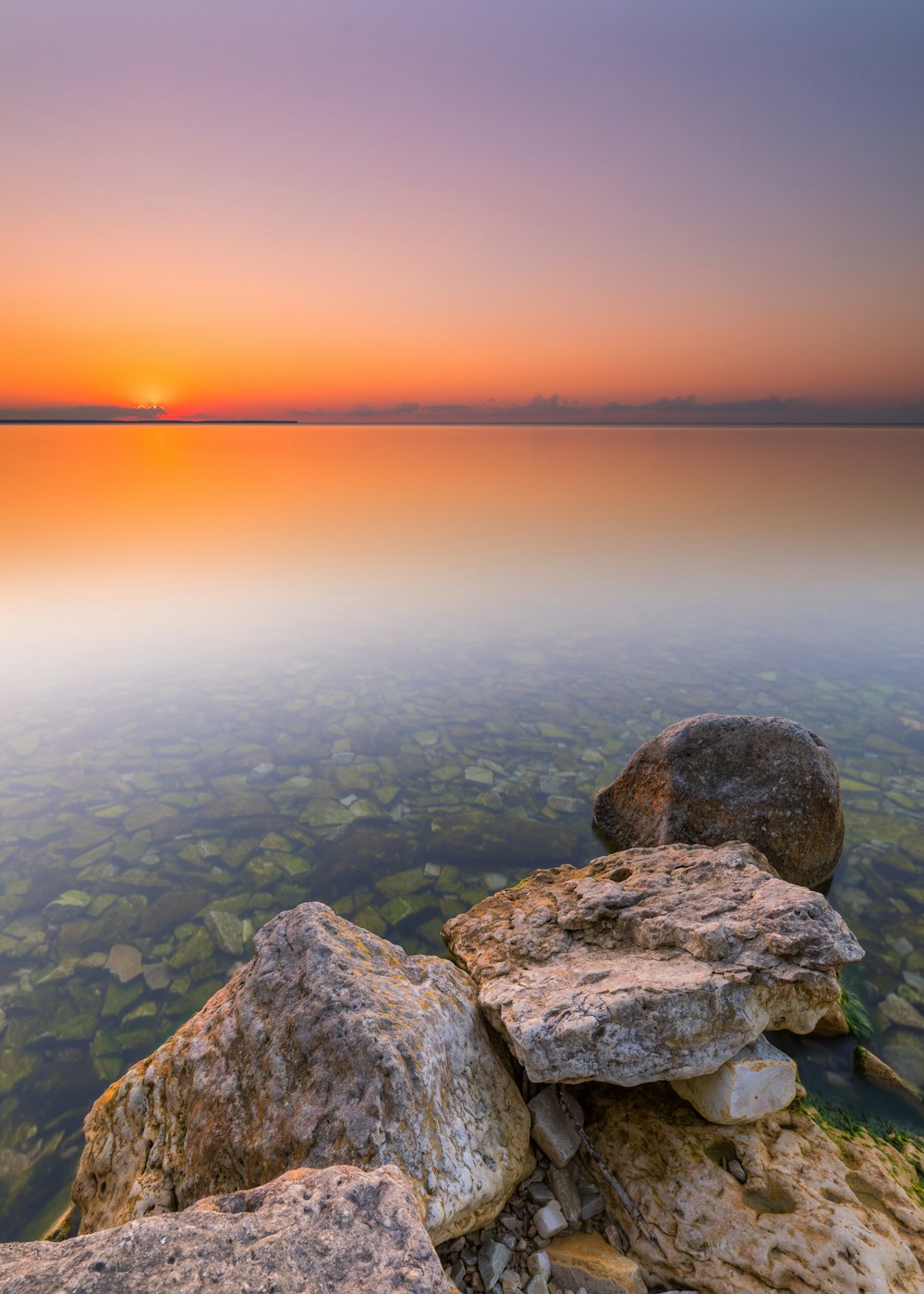 roches grises et brunes près du plan d’eau au coucher du soleil