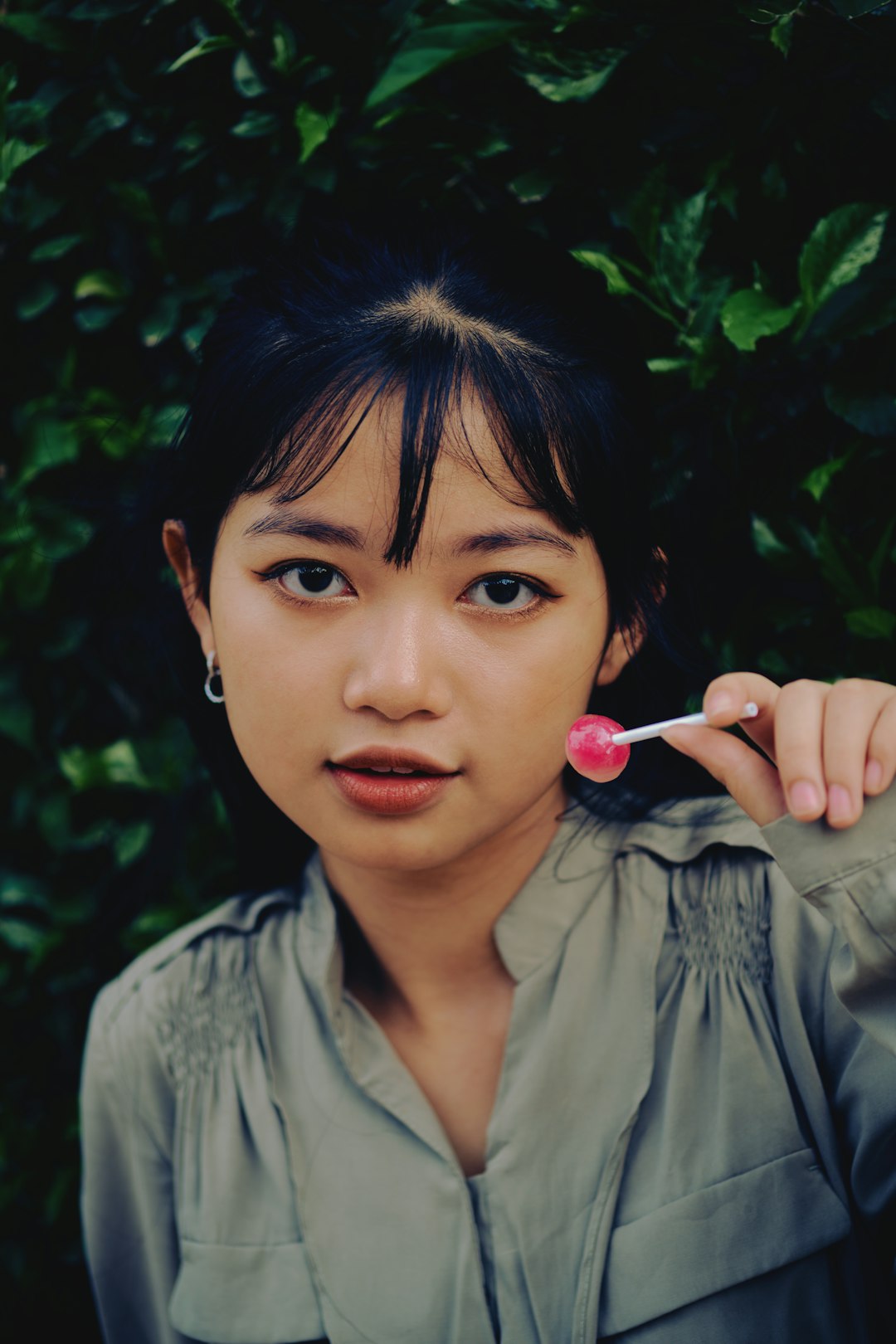 woman in gray button up shirt holding pink lollipop