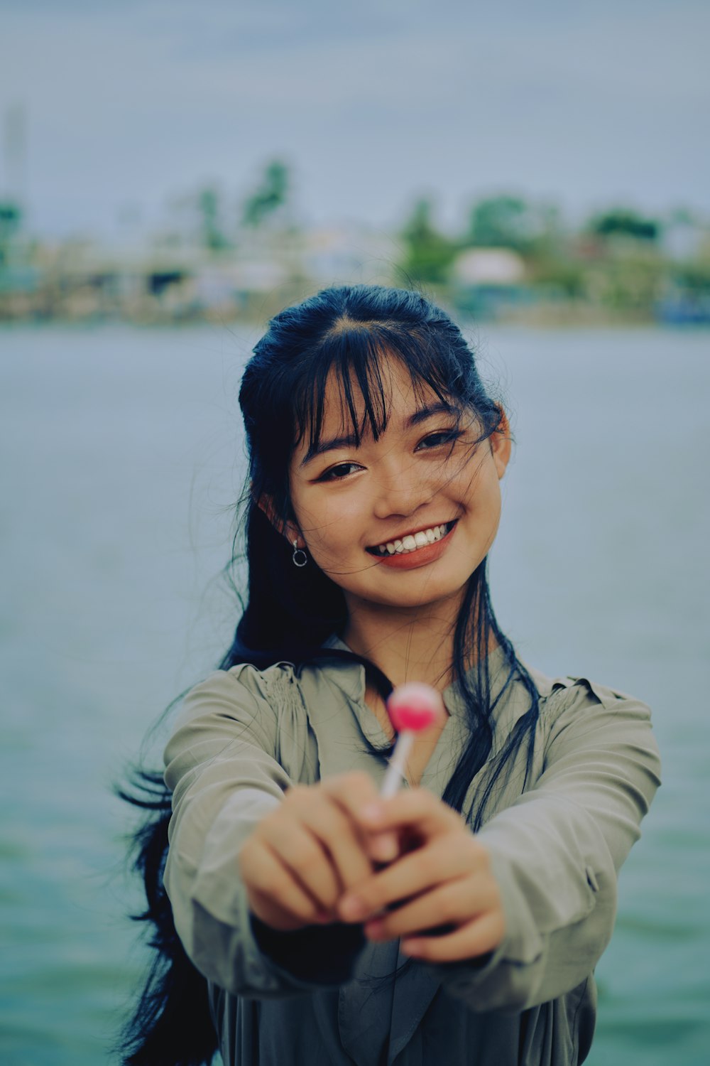 smiling woman in gray jacket holding white cotton candy during daytime