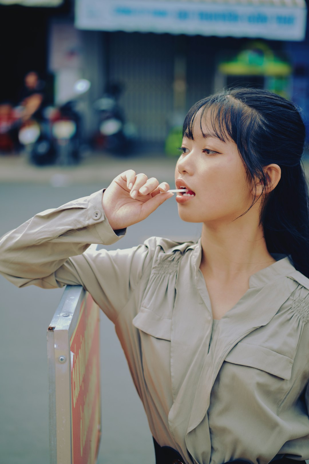 woman in beige button up shirt holding white cigarette stick