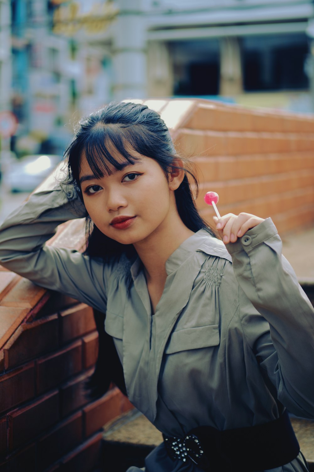 girl in gray jacket holding pink lollipop