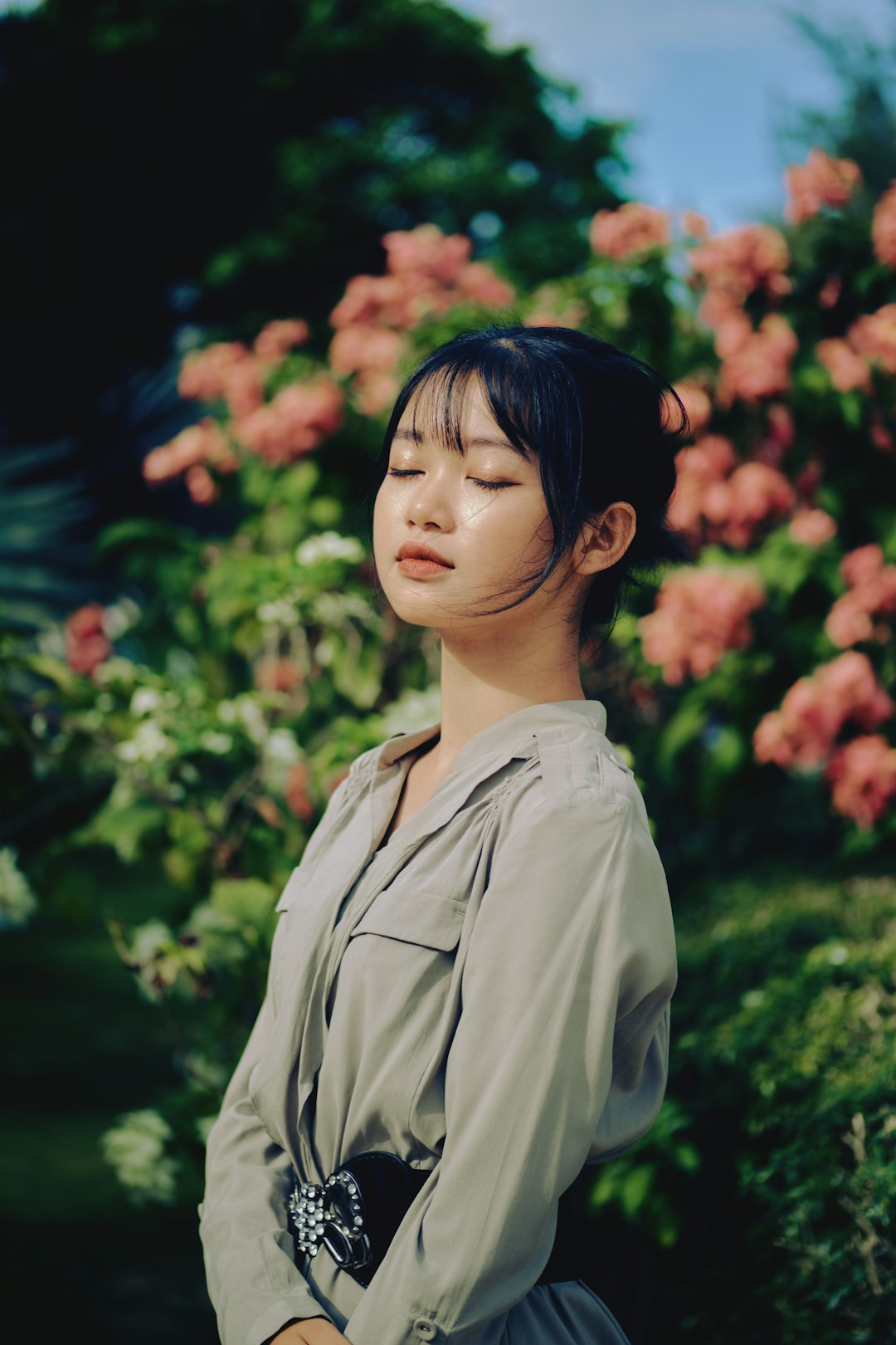 woman in gray button up shirt standing near green plants during daytime