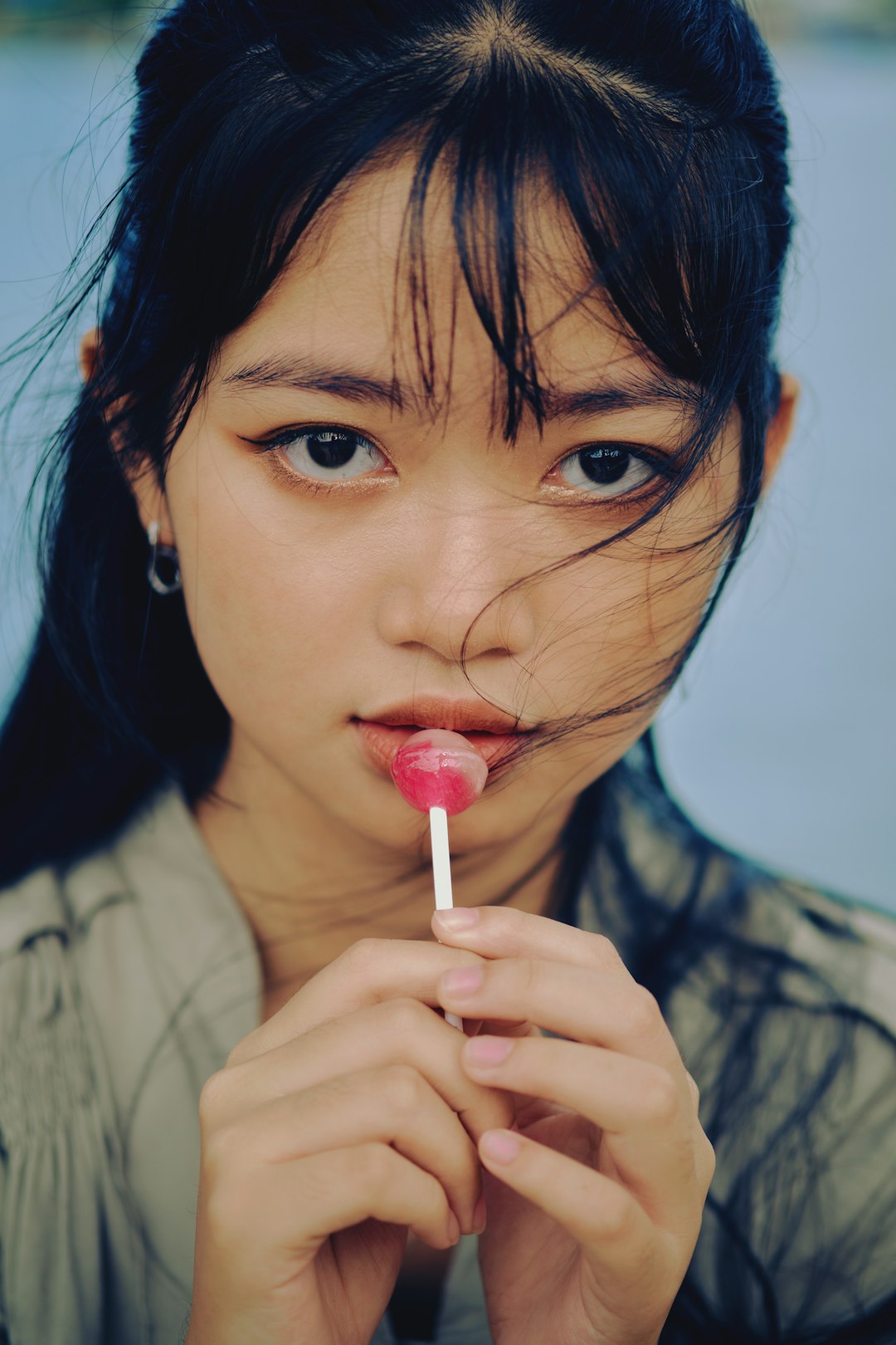 woman in gray shirt holding red lollipop