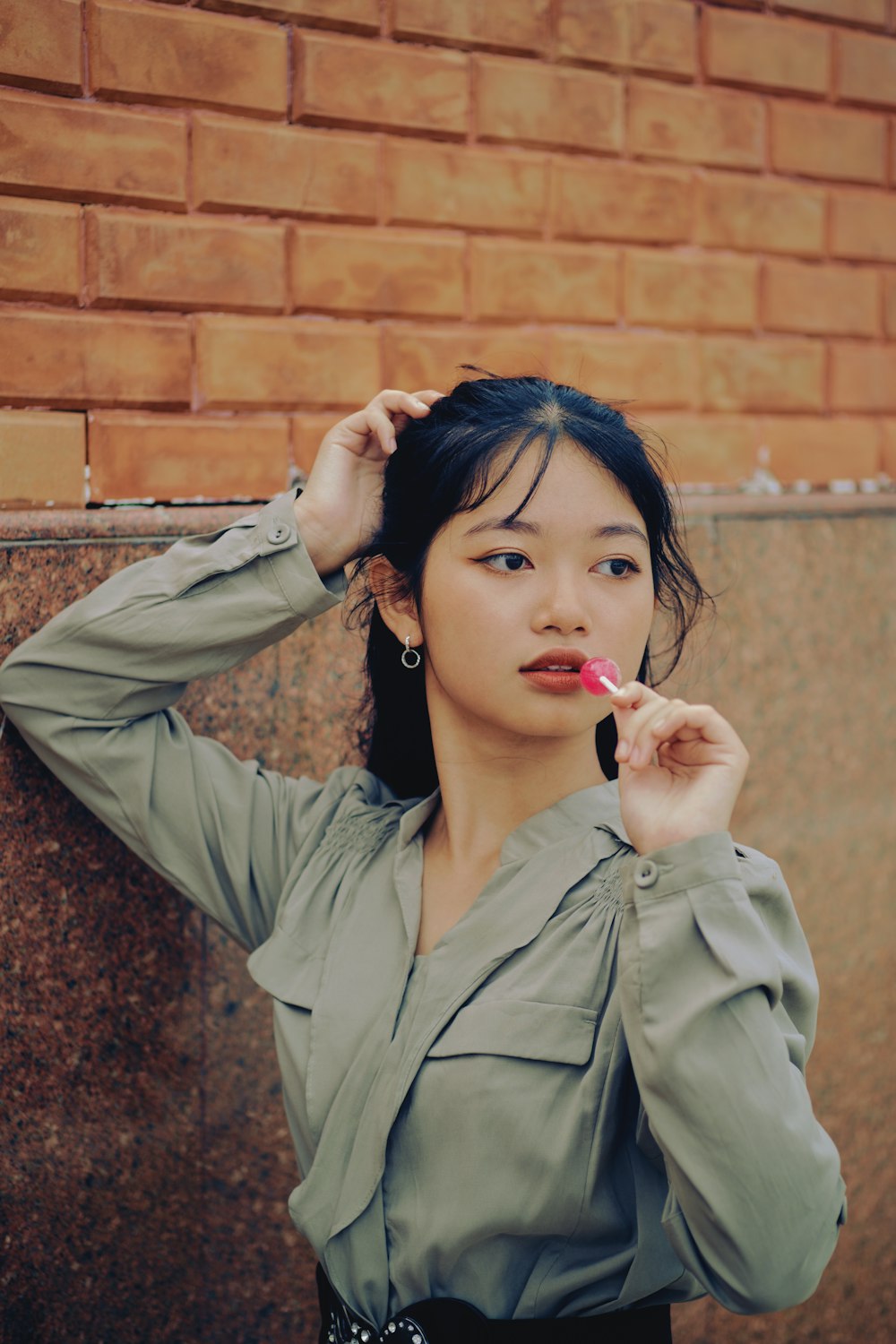 woman in gray coat holding red lollipop