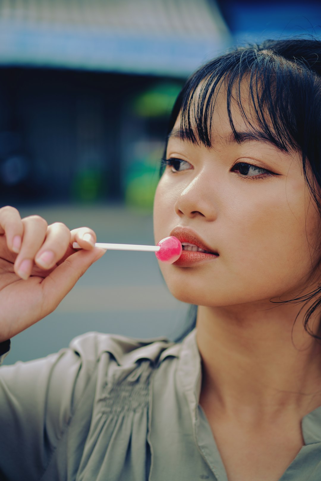 woman in gray shirt holding pink lollipop