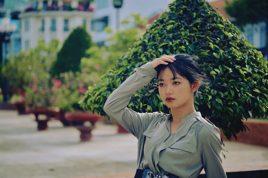 woman in gray jacket standing near green plant during daytime