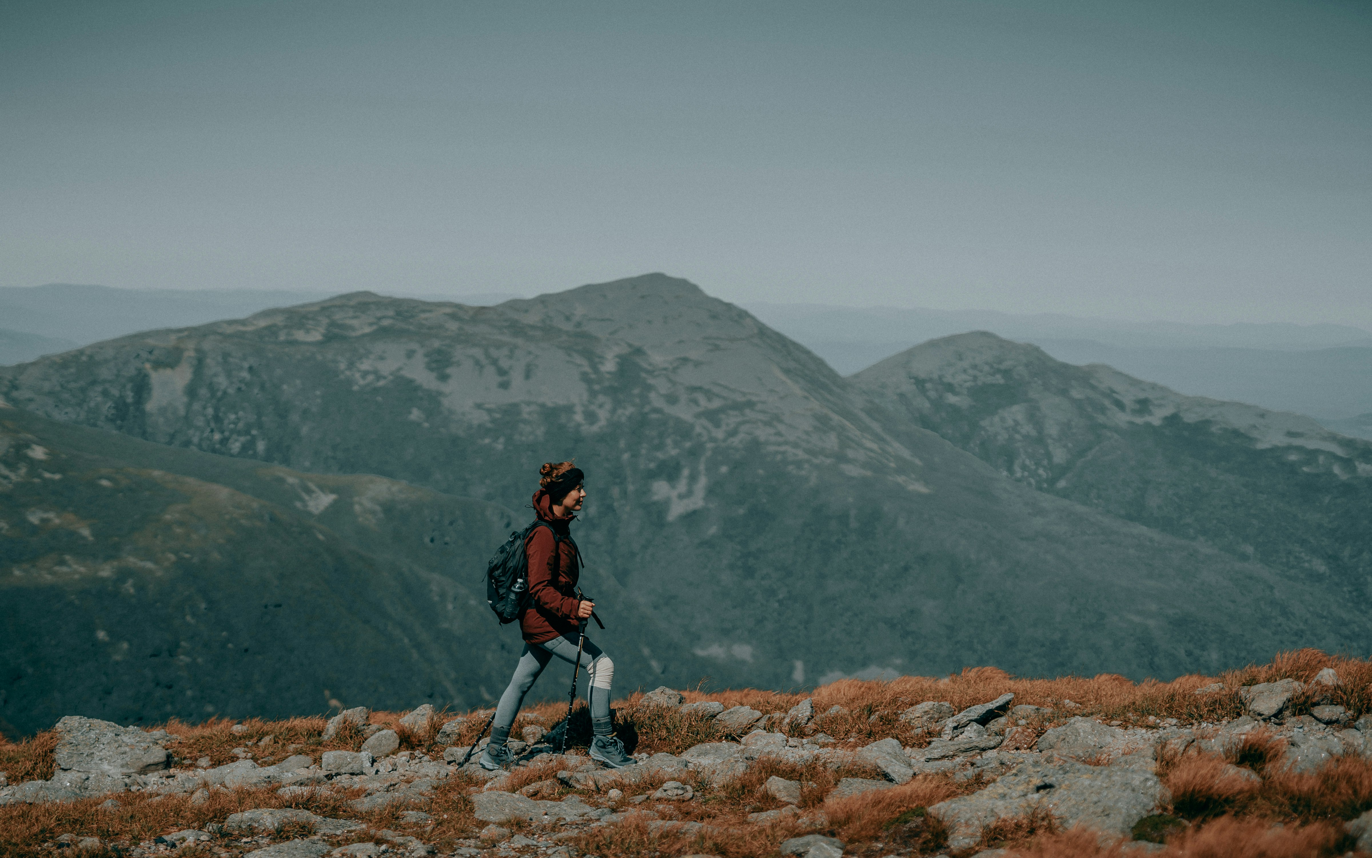 man in black jacket and black pants standing on rocky hill during daytime