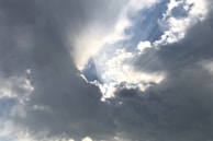 Soft rays of light breaking through dark clouds, symbolizing revelation and clarity.