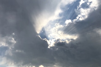 Soft rays of light breaking through dark clouds, symbolizing revelation and clarity.