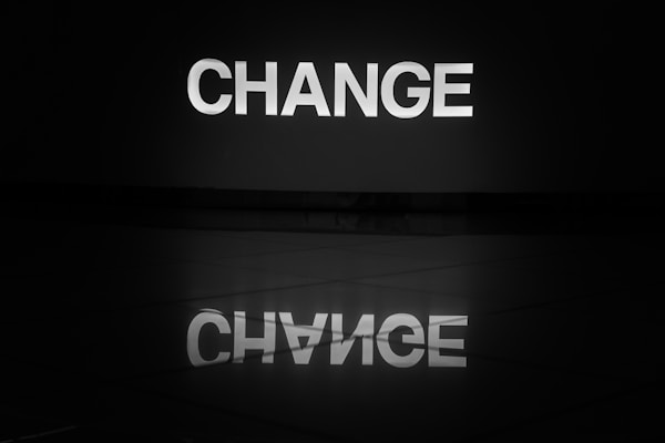 The word change illuminated in white and reflected on a tiled floor.by Nick Fewings