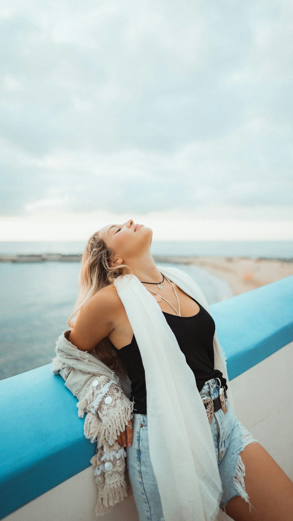 woman in black tank top and white lace cardigan sitting on blue and white boat during