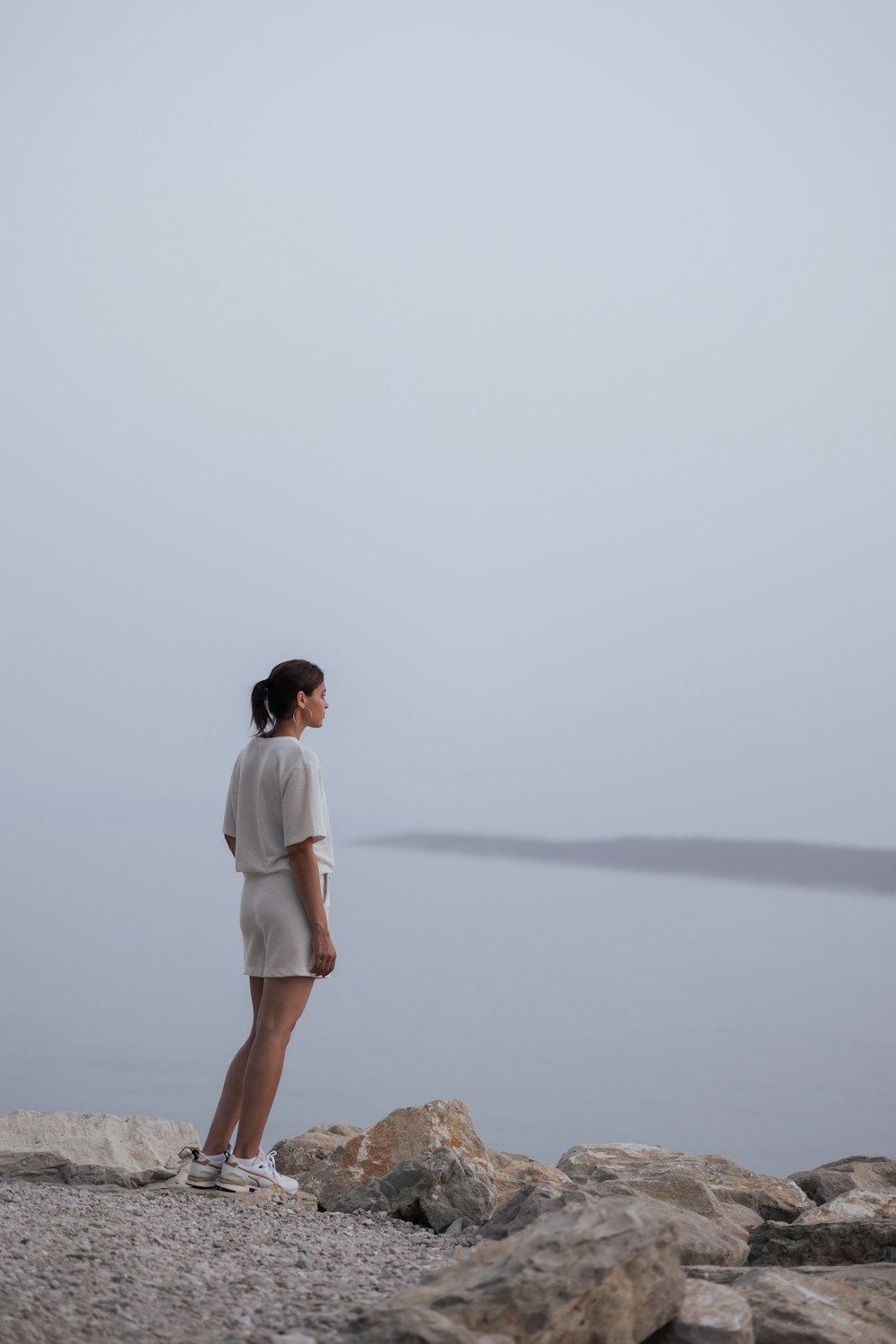 man in white t-shirt and brown shorts standing on brown sand during daytime