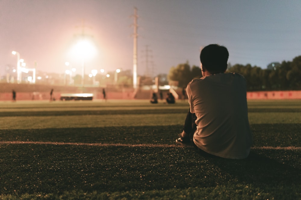 man in brown shirt sitting on green grass field during daytime