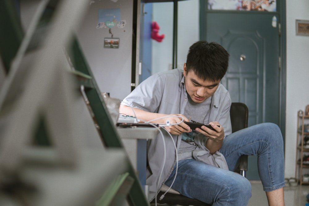 man in white dress shirt and blue denim jeans sitting on chair