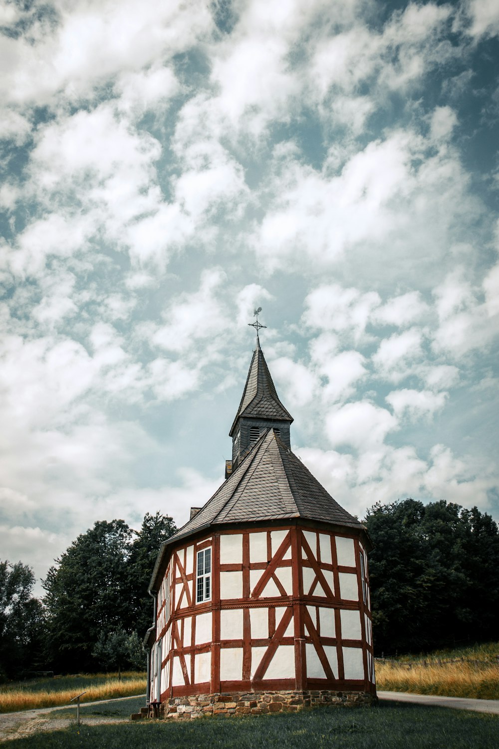 ein kleines rundes Gebäude mit einem Kirchturm und einem Kreuz auf der Spitze