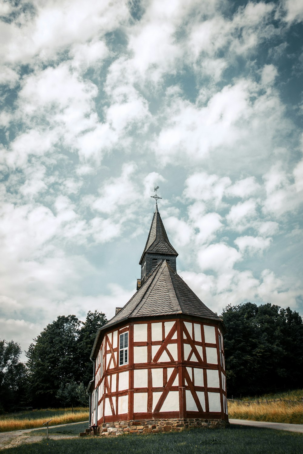 a small round building with a steeple and a cross on top