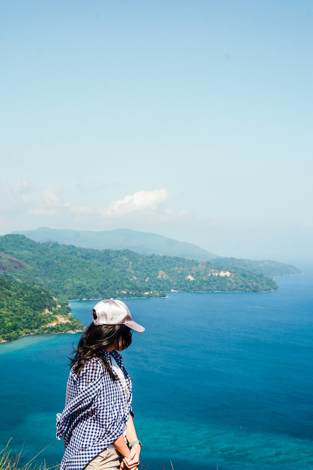 woman in white hat standing on top of mountain during daytime