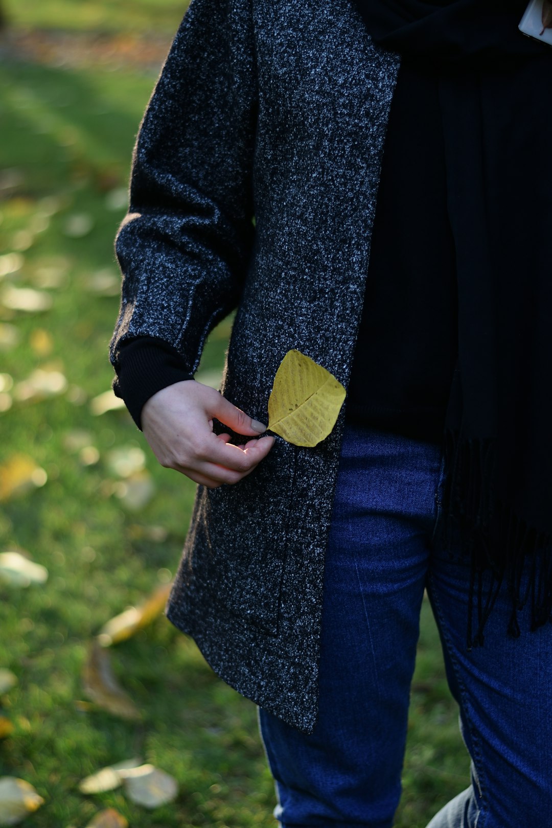 person in blue coat holding yellow leaf