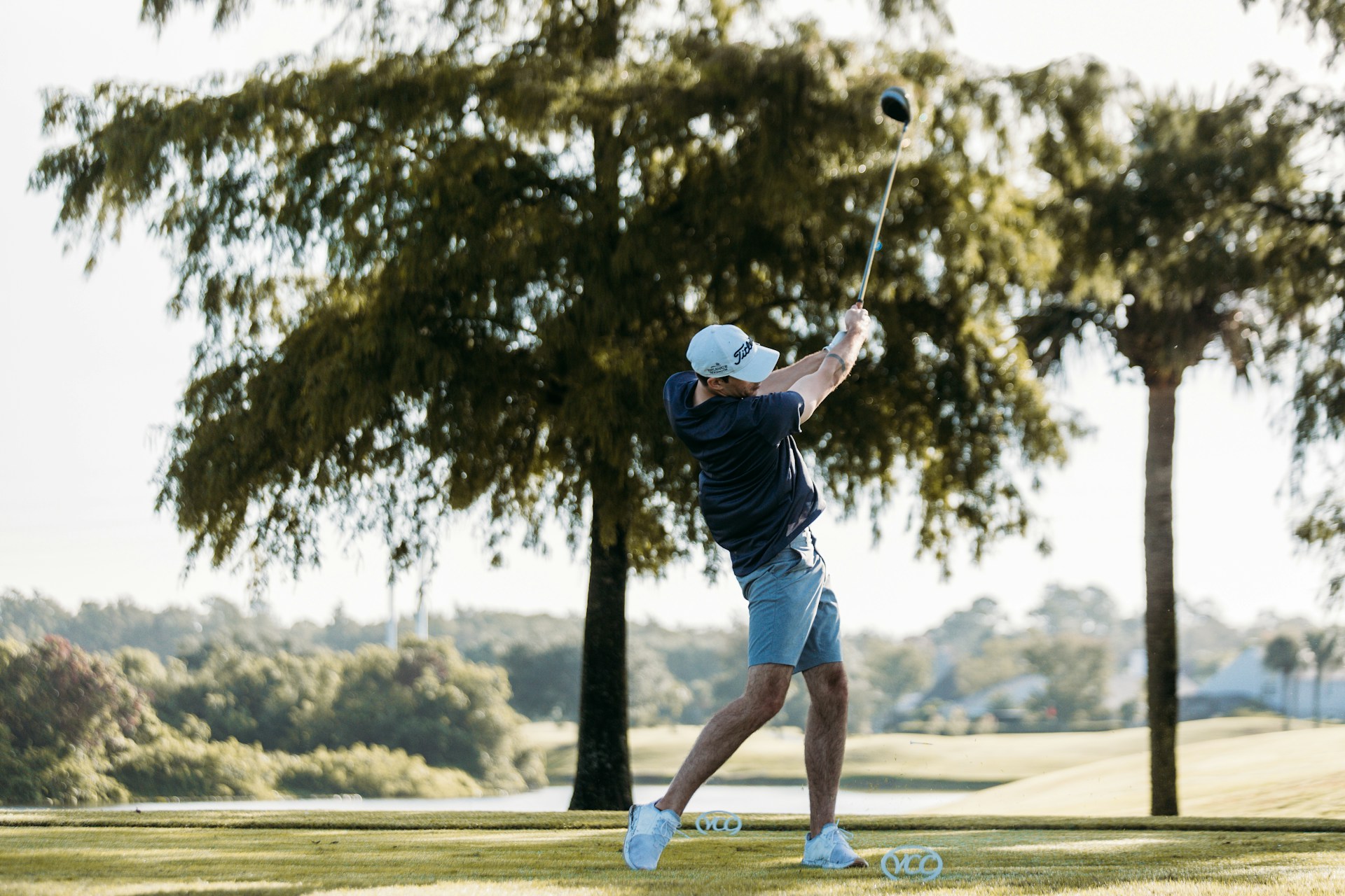 A golfer in mid-swing, capturing the dynamic motion against a lush green backdrop.
