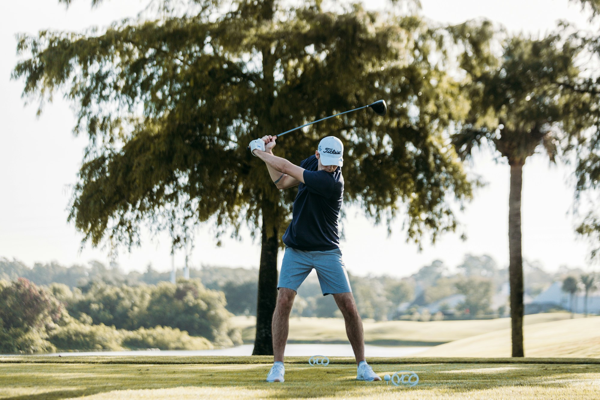 a man swinging a golf club on a golf course with a high handicap