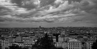 A dramatic black and white cityscape showing tall buildings under cloudy skies.