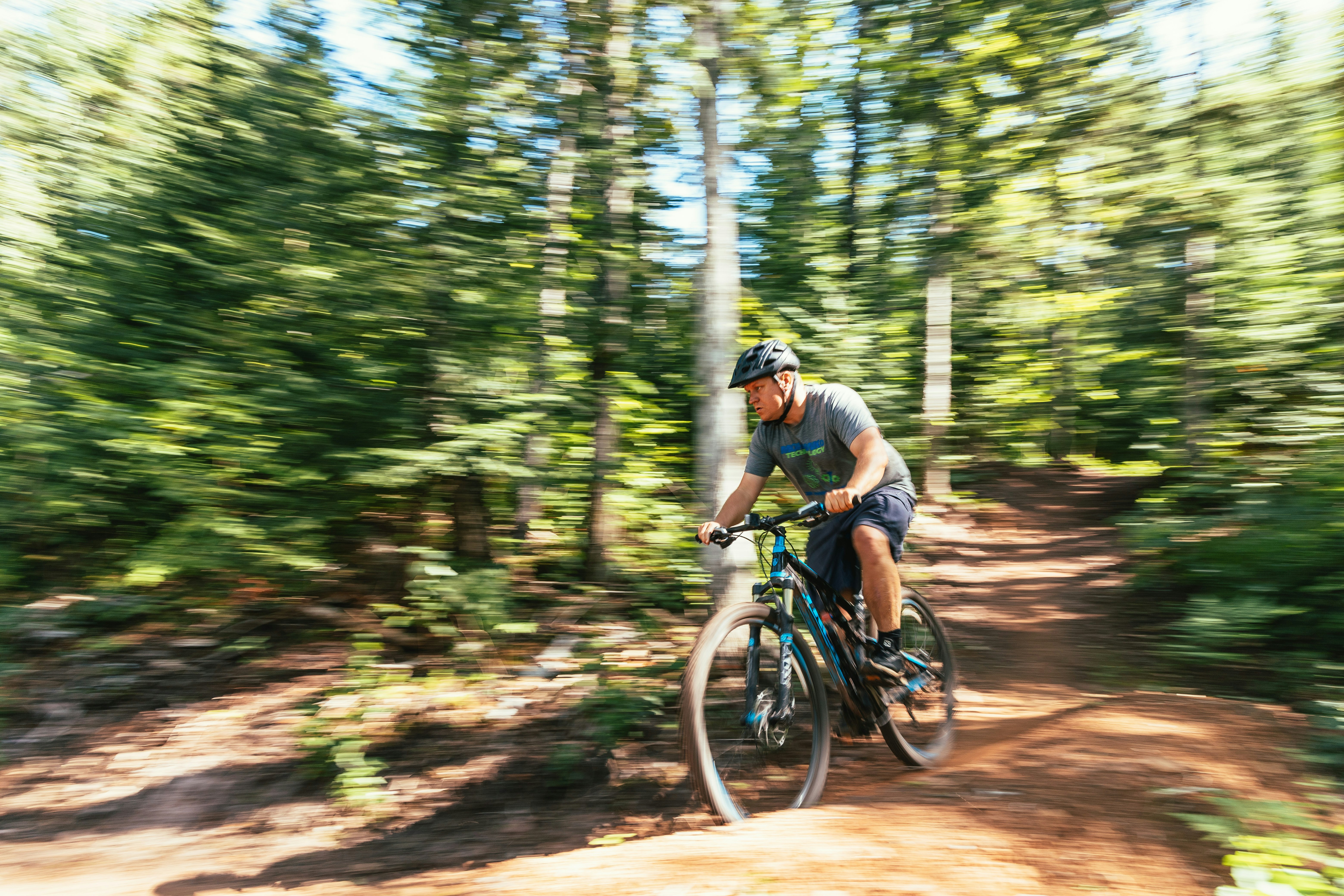 man in green shirt riding on bicycle in forest during daytime