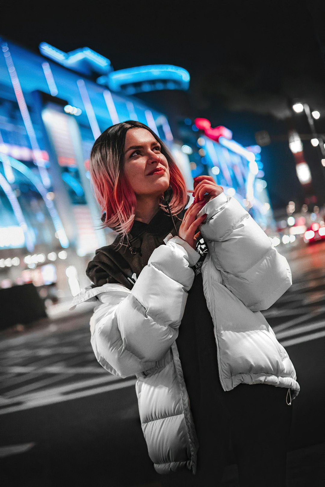 woman in white coat standing on street during night time