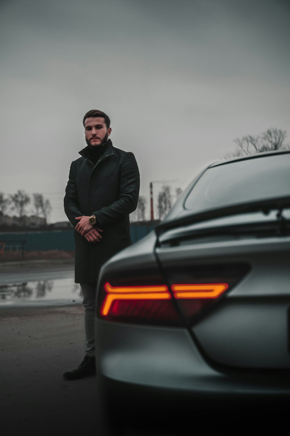 man in black jacket standing beside black car