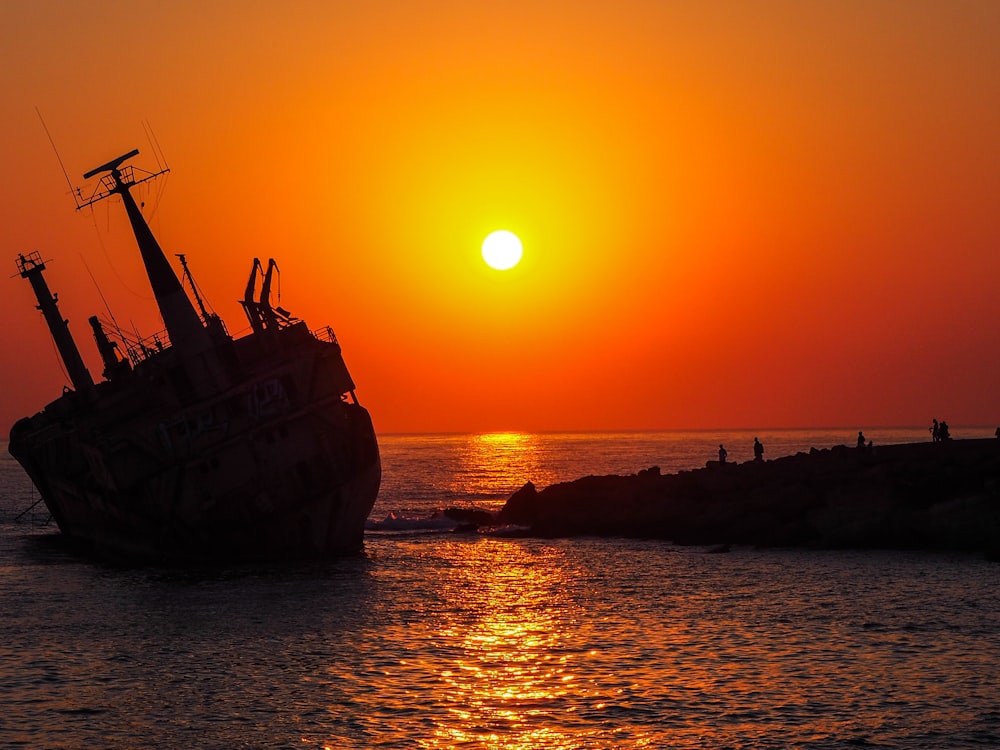 navire brun sur la mer au coucher du soleil