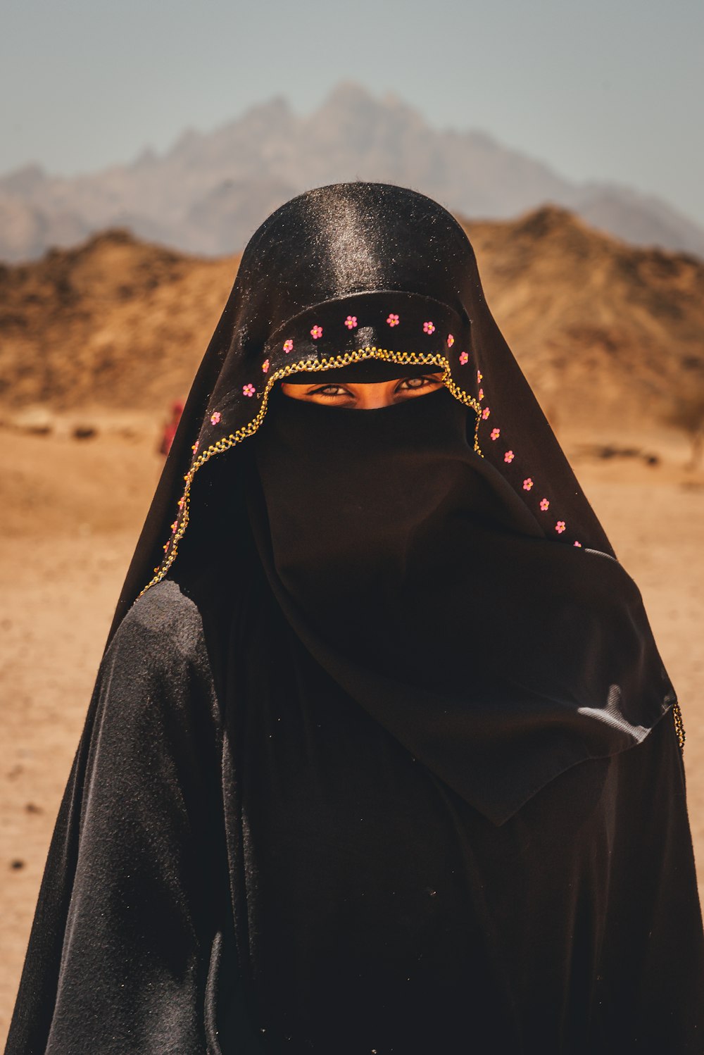 person in black hijab standing on brown field during daytime